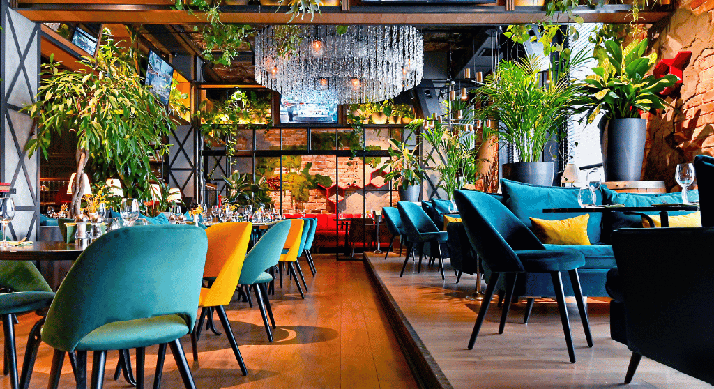 Restaurant with colourful furniture and many green plants